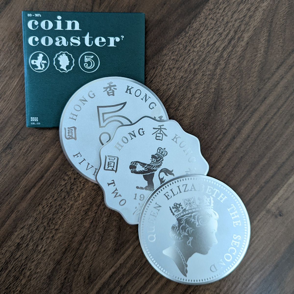 Product packaging and the three included coasters of the Stainless Steel Coin Coaster